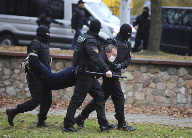 En man bärs iväg i armar och ben vid en demonstration i Minsk, den 1 november i fjol. Arkivbild.