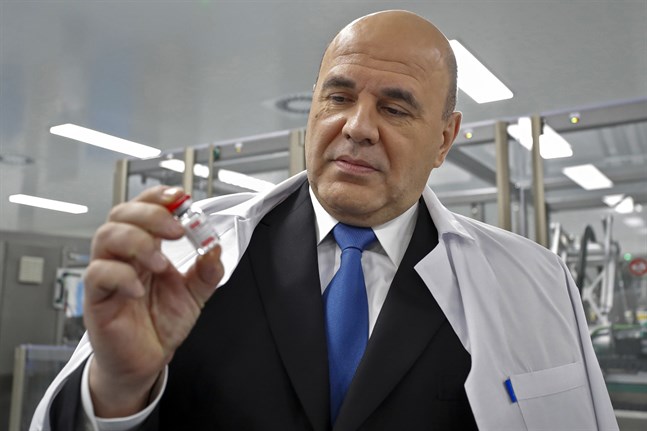 Rysslands premiärminister betraktar en dos av det ryska vaccinet Sputnik V vid en fabrik utanför S:t Petersburg. Bilden är från den 25 december.
