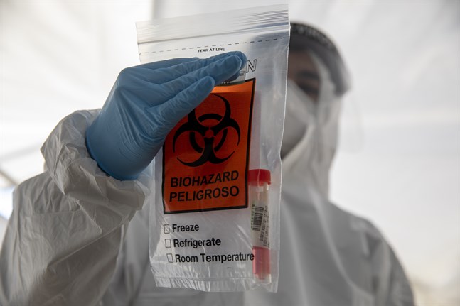 En vårdanställd på ett testcenter i Jerusalem håller upp en plastpåse som innehåller ett covid-19-test.
