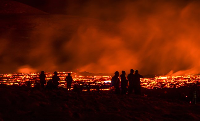 Besökare i Fagradalsfjäll på Island betraktar lava som strömmar från vulkanen.