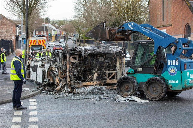 Stadens anställda städar upp efter nattens oroligheter. Här är det en buss som stuckits i brand, som forslas bort från Shankill Road i Belfast.