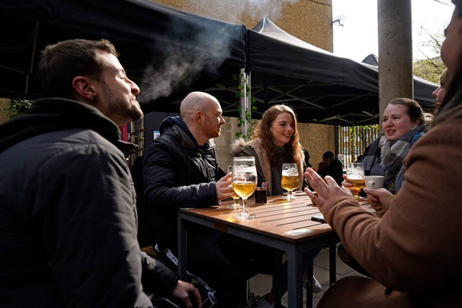 Upp till sex personer får samlas tillsammans utomhus. Det här sällskapet njuter på en uteservering i östra London.