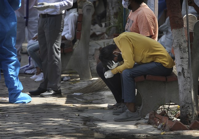 Sörjande anhöriga samlas för kremation av en person som nyligen avlidit i sviterna av covid-19 i Delhi, Indien.