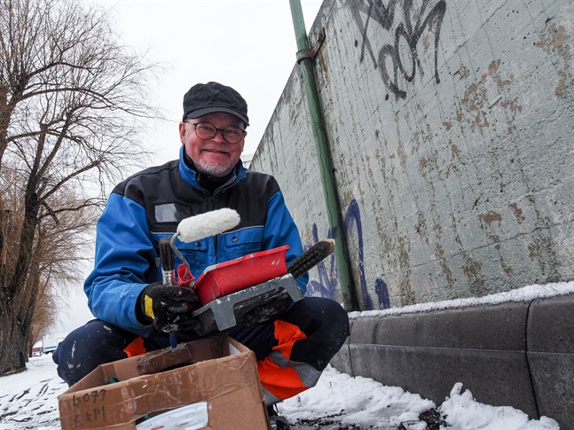 Här har Tom Tiainen klätt ut sig till gatuarbetare. Ingen har ännu märkt av att han utan lov i flera dagar skrubbat bort klotter och målat stadens fasader i grått.