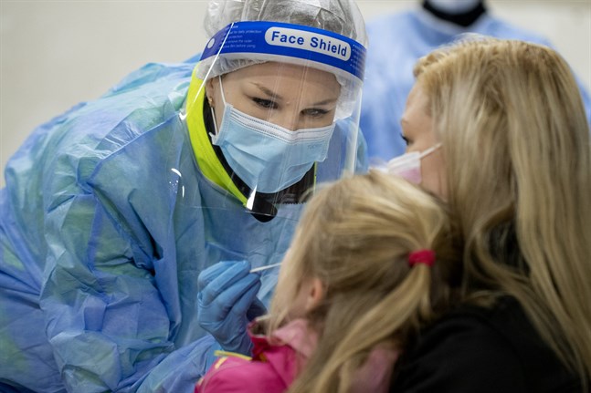 Närvårdaren Jenny Järvi tar coronaprov av Terhi Lamminen och dottern Veera.