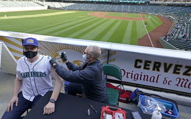 Den avtagande vaccinationstakten i USA oroar, men här får Seattle Mariners-supportern Hunter Moreira sitt covidvaccin före basebollmatchen mot Baltimore Orioles.