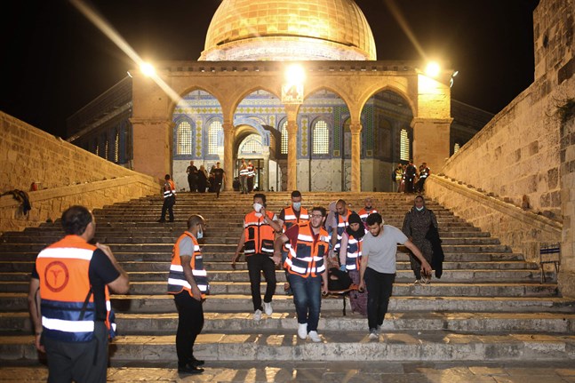 Palestinska vårdare evakuerar en person som skadats under en sammandrabbning mellan israelisk polis och palestinska demonstranter i Jerusalem. Läget i Jerusalem är det värsta på flera år.