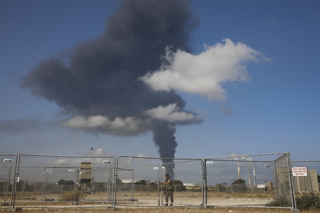 En israelisk soldat framför en rökplym från en oljetank som träffats av raketer från Gaza. Bilden är från tidigare i veckan.