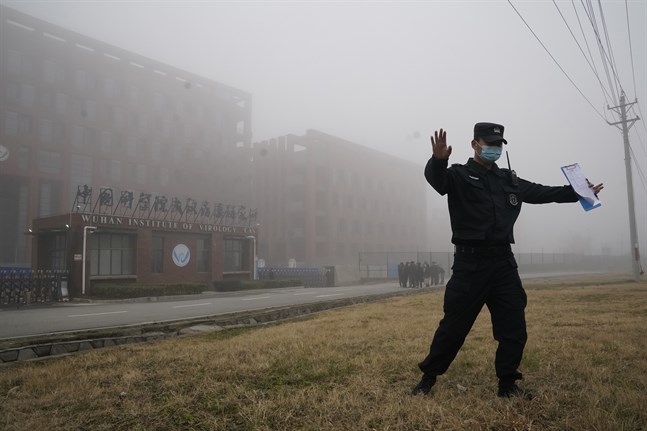 En säkerhetsvakt motar bort journalister från det laboratorium i Wuhan, där sars-cov2-viruset uppstod enligt vissa teorier. Arkivbild.