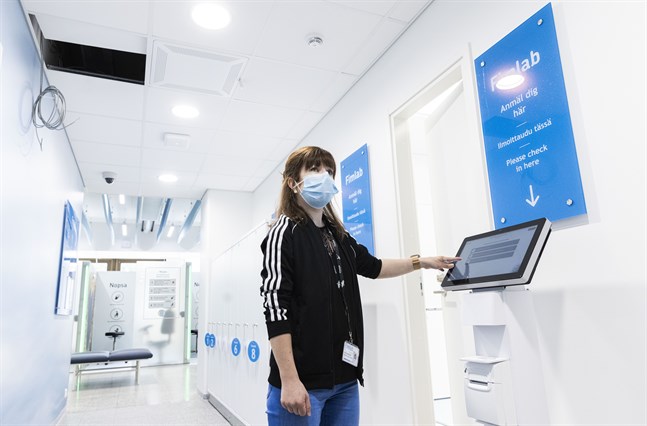 Daniela Utriainen-Agengo visar var kunderna börjar sitt besök i Fimlabs nya laboratorium – vid anmälningsautomaterna.