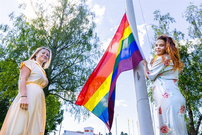 Isabel Flemming och Linn Nyholm hissar prideflaggan vid Övermalax uf.