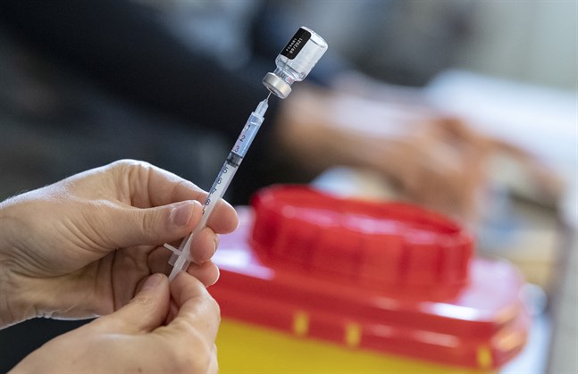 En spruta fylls från en ampull med Comirnaty vaccin från Pfizer-Biontech. Arkivbild.