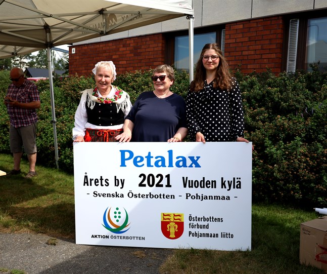 Petalax hembygdsförening ordförande Kerstin Knip till vänster. Kristina Vesterback i mitten är aktiv inom föreningen Arbetsgruppen för Petalax. Till vänster står Frida Lähdesmäki som är byaombud i Aktion Österbotten. Alla tre håller upp skylten som kommer att placeras på Strandvägen.