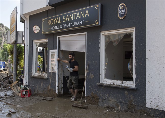 En man står framför sin restaurang som förstörts i översvämningarna i Altenahr, Tyskland.