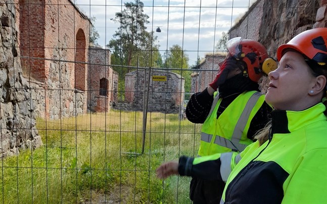 Eija Saukkoriipi, längst fram, och Pauliina Koivunen inspekterar området på muren där väder och vind har tryckt ut stenar, vilket utgör en säkerhetsrisk.