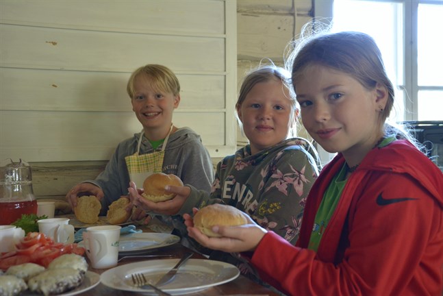 Lea Ingberg, Alma Backfolk och Anton Nordström visar upp sina hembakade hamburgerbröd som de gjorde under tisdagen i matskolan på Vargberget.