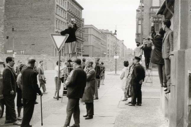 En kvinna i Västberlin vinkar till människorna på andra sidan muren vid Bernauer Straße i slutet av augusti 1961. Till en början var muren så pass låg så att man kunde kika över med en stege.