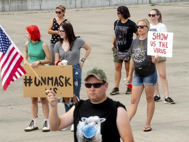 "Visa oss viruset" står det på Valerie Sharps plakat (till höger). Hon protesterar mot ett lokalt munskyddstvång för skolelever i Flint i Michigan.