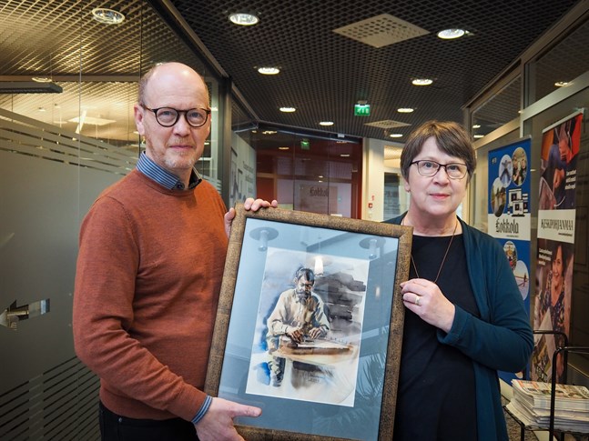 Heikki Nisonen och Riita Rauhala visar Esa Tiainens "Kantelespelaren" från 2019. Bland annat den kan man vinna i lotteriet på MÖK:s konserter.
