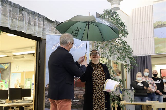 Norra Korsholms skolas rektor Robert Backman överräcker paraplyet med texten "Du är guld värd" till Camilla Forsberg.