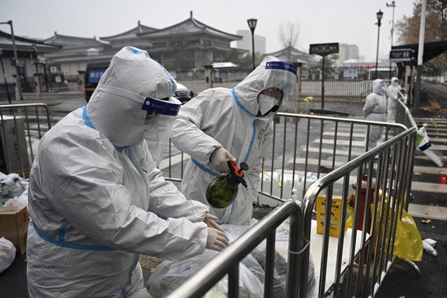 Hälsoarbetare i Xi'an desinficerar matkassar. Invånarna är beordrade att stanna hemma efter ett ökat antal virusfall i staden.