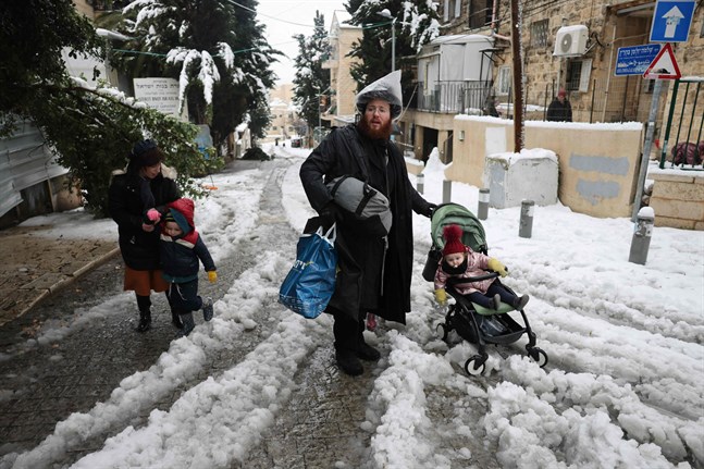 En familj försöker ta sig fram på en snötäckt gata i Jerusalem.