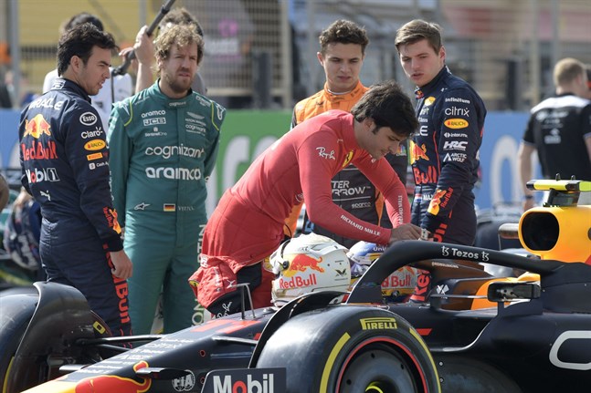 Ferrariföraren Carlos Sainz inspekterar Red Bulls bil under uppsikt av Sergio Perez, Aston Martins Sebastian Vettel, McLarens Lando Norris och Red Bulls Max Verstappen.