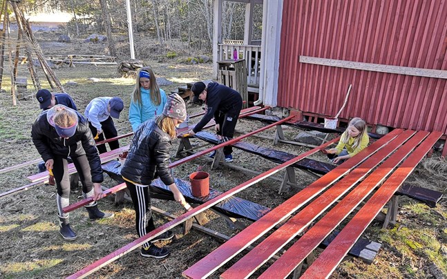 De nya bräderna stryks med rödmylla innan de sätts på plats. Här målar Celina Nummela och Lotte Björklund längst framme. Bakom från vänster Miro Hautaviita, Neo Aittamäki, Leah Erlands, Alvar Berglund och Kajsa Grankull.
