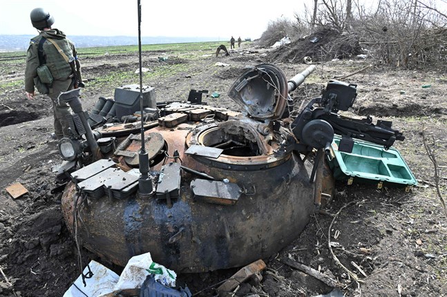 En ukrainsk soldat står bredvid en nedbrunnen rysk pansarvagn i östra Charkiv.