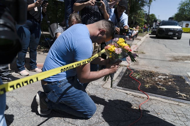 En sörjande man håller en bukett blommor vid polisavspärrningarna utanför Robb Elementary School i Uvalde, Texas.