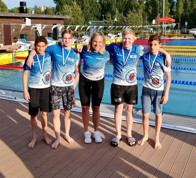 Michail Karagiannis, Sylvester Pihlaja, Anton Qvisén och Konstantinos Karagiannis tog silver i 4x100 meter medley i 13-årsklassen. I mitten tränaren och lagledaren Sara Riska.