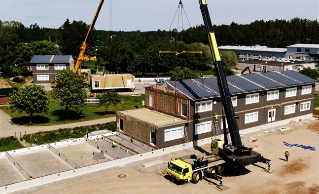 Ett tiotal personer arbetar med att separera, lyfta, placera och fästa de stora modulerna som bildar en 1500 kvadratmeter stor skolbyggnad.