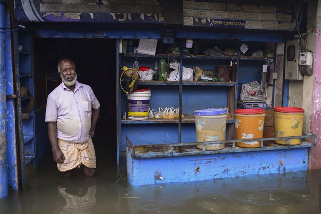 En man står i dörröppningen till sin översvämmade affär i Sylhet, Bangladesh.