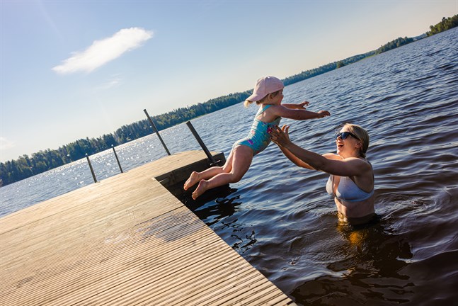 Lyra Strand plumsar i vattnet med stor entusiasm. Jessica Österberg har längtat efter varma sommardagar på Karperö badstrand.