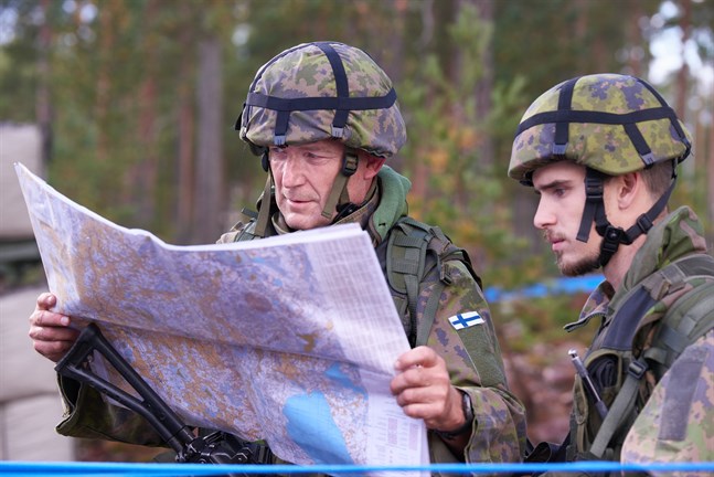 Sverker Skogberg och Elias Andersson studerar kartan ute i terrängen på garnisonsområdet.